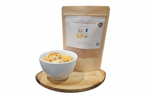 Bacon Cheddar Ranch Gourmet Snack Mix next to a bowl on a wooded cutting board