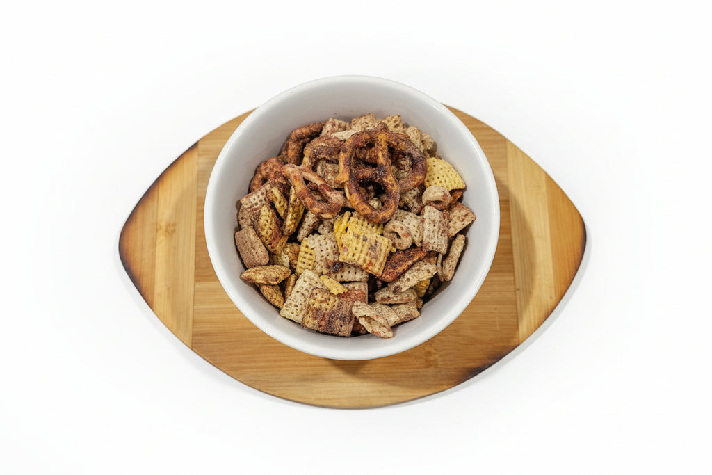 White bowl with Chocolate covered cherries snack mix on a wooden coaster