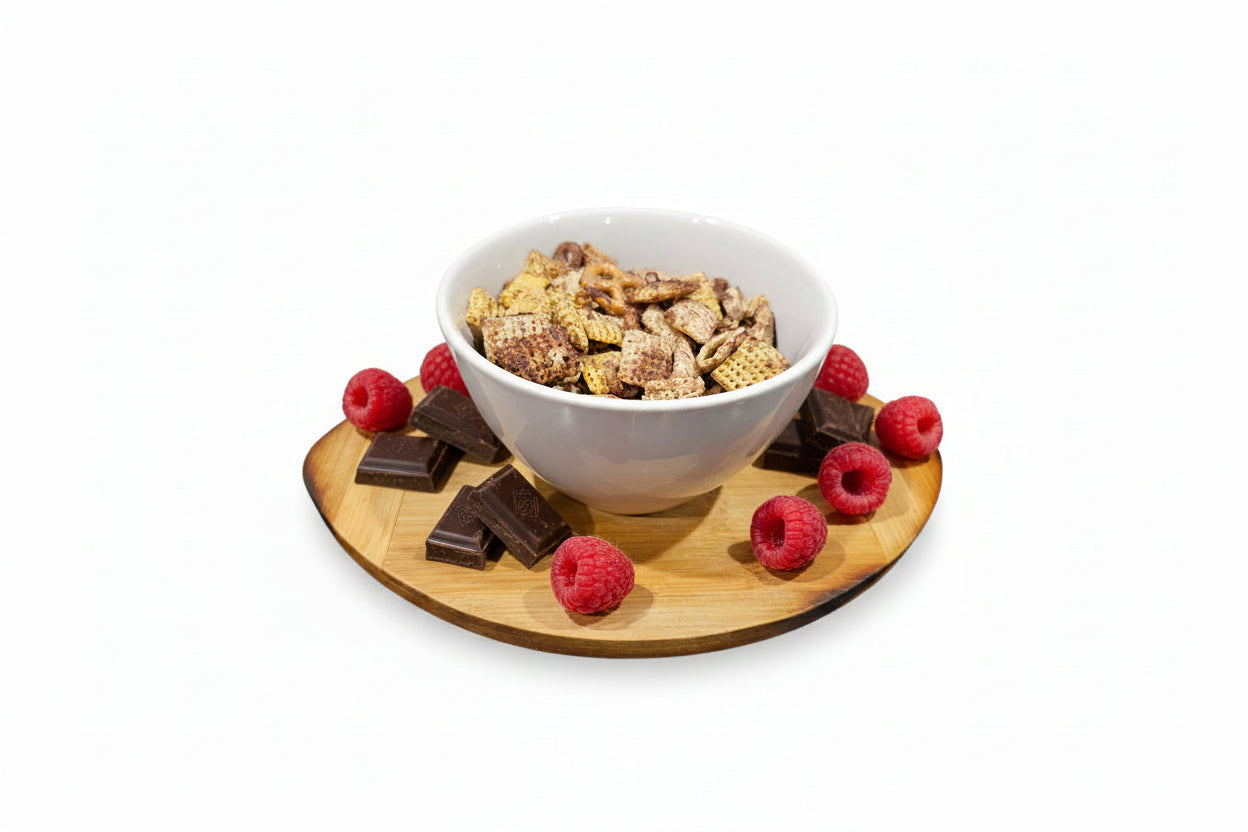 White bowl with snack mix on a wooden coaster on a white background