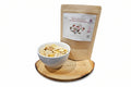 White bowl with snack mix on a wooden cutting board next to a package of snack mix