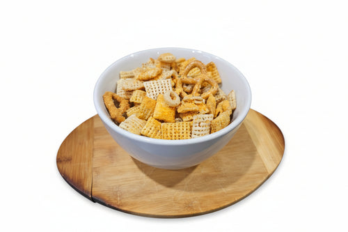 White bowl filled with cheddar sour  cream and onion snack mix on a wooden cutting board