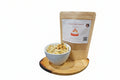 Bag of snack mix with a bowl of snacks on a wooden tray against a white background