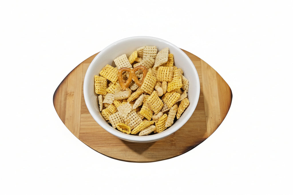 White bowl filled with snack mix on a wooden cutting board